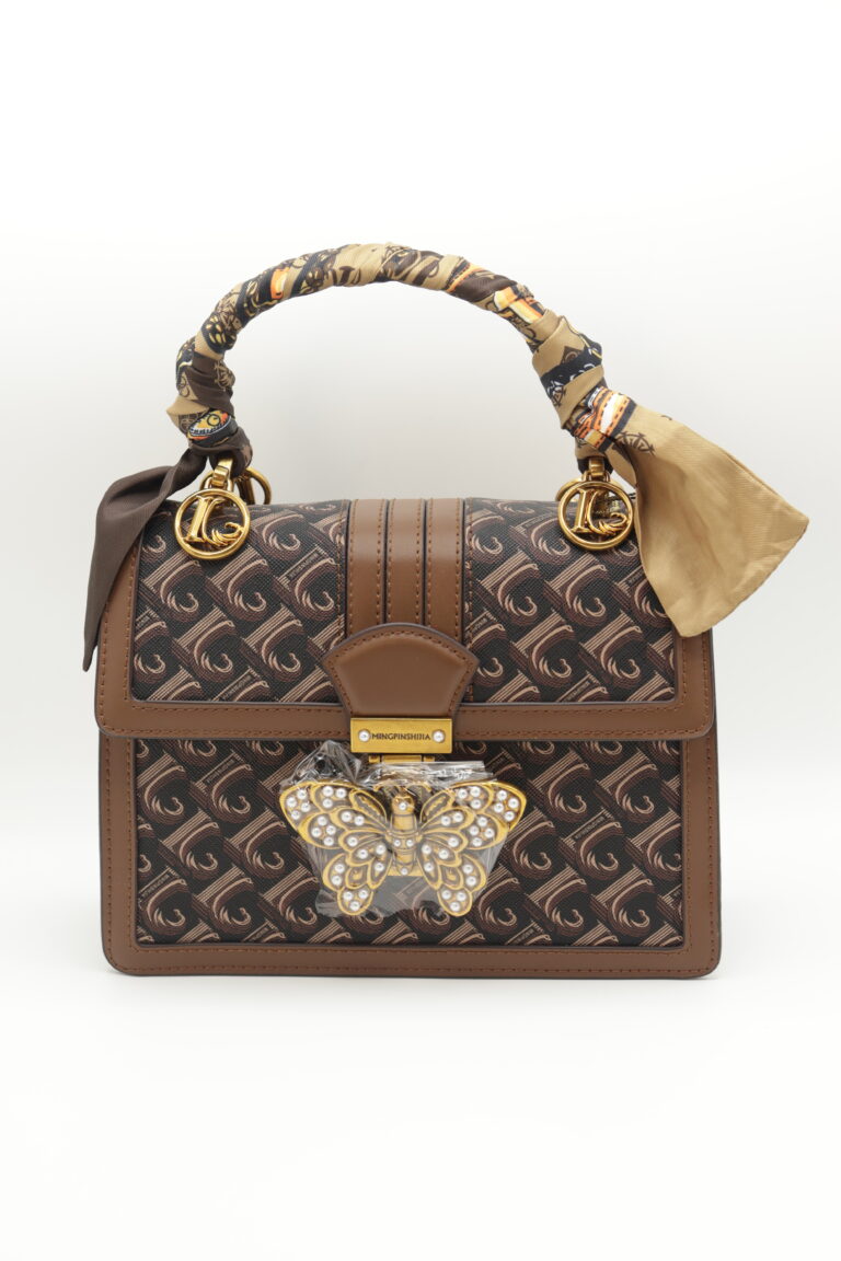Chocolate Butterfly Luxe Bag, front view — chocolate monogram canvas with tan leather trim, gold ring clasps, silk twilly scarf wrapped on the top handle and a crystal butterfly charm on the front flap